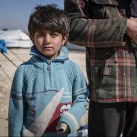 In this picture taken Feb. 16, a Syrian school teacher from Deir Ezzour stands with his son and daughter in Al Hol Camp, Hasakah Governorate, Syria. A new report by Save the Children says Syrian children are showing symptoms of ‘toxic stress’ from war exposure, and attempting self-harm and suicide. Syrian children show signs of severe 'toxic stress' from prolonged war exposure
