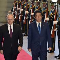 Prime Minister Shinzo Abe and Russian President Vladimir Putin walk past honor guards as they arrive at Abe\'s official residence in Tokyo on Dec. 16. Abe is reportedly visiting Russia later next month for talks with Putin. | VIA BLOOMBERG