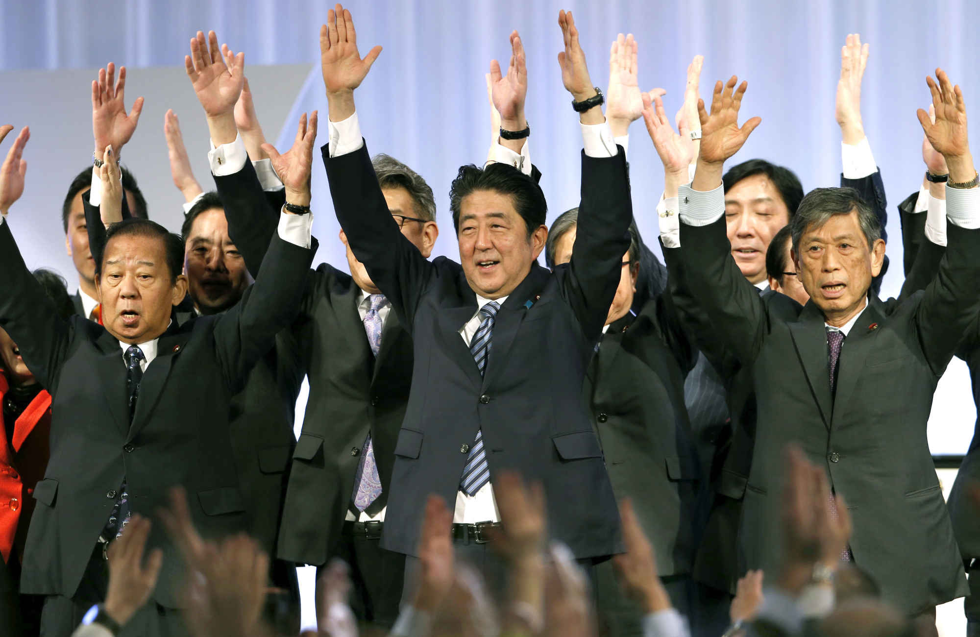 Prime Minister Shinzo Abe (center) shouts traditional banzai cheers with lawmakers and members of his ruling Liberal Democratic Party during its annual convention at a Tokyo hotel Sunday. | AP