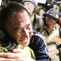 Hiroji Yamashiro, a prominent anti-U.S. base activist in Okinawa, hugs a supporter Saturday after being released on bail after five months of detention in Naha, Okinawa Prefecture. | KYODO