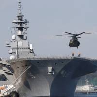 A helicopter lands on the Izumo, the Maritime Self-Defense Force\'s largest helicopter carrier, at Yokosuka, Kanagawa Prefecture, in December. | REUTERS