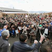 Visitors to the new shopping center in tsunami-hit Minamisanriku, Miyagi Prefecture, try to catch bags of rice cakes that were thrown to the crowd in celebration of its opening on Friday. | KYODO