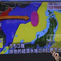 A woman walks past a screen showing a TV news program on a missile firing by North Korea with a map of Japan and North Korea in Tokyo on Monday. | AP