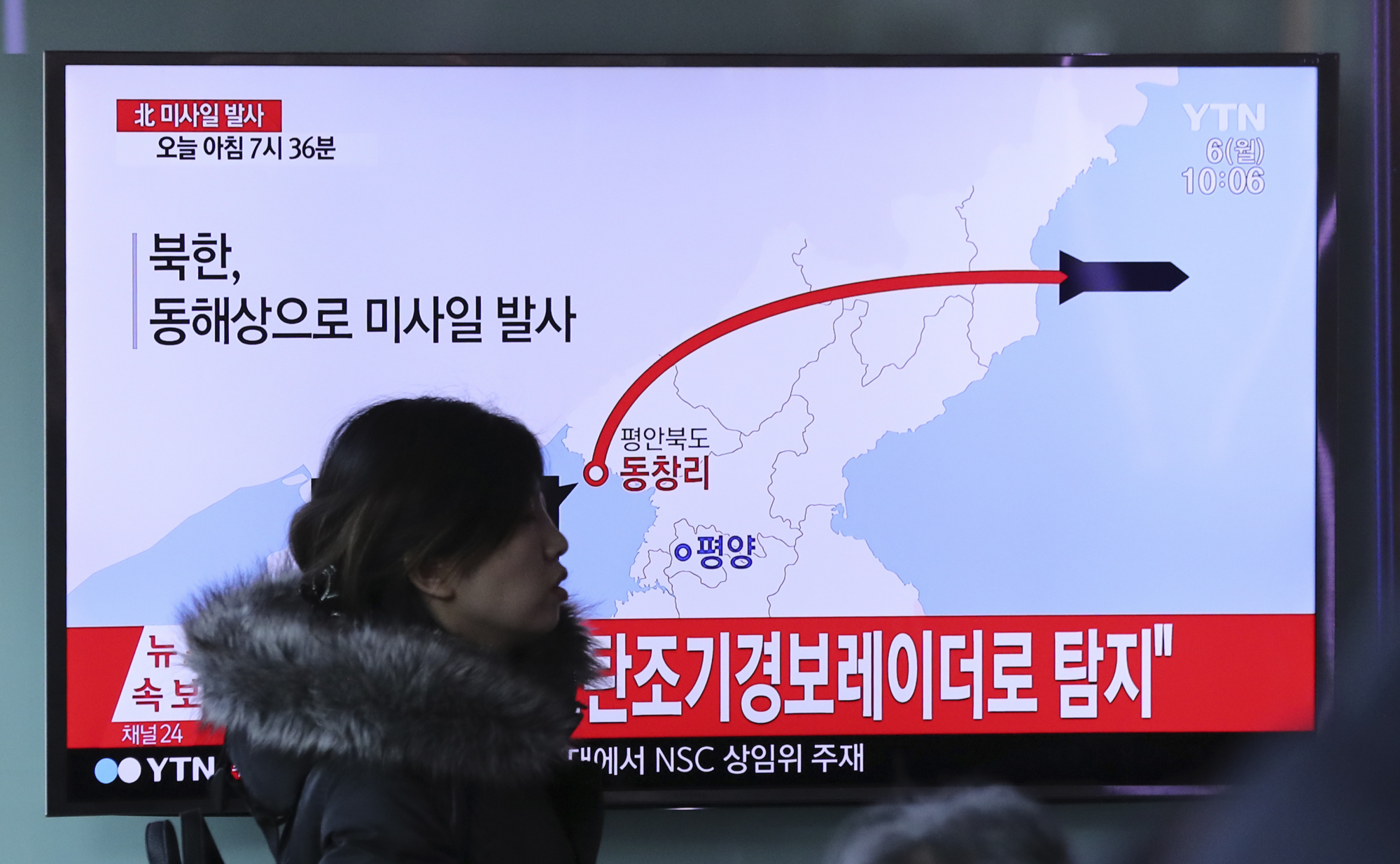A woman walks in front of a TV screen at Seoul Train Station showing a news program reporting on North Korea's firing of four missiles Monday. | AP