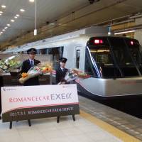 Odakyu Electric Railway Co. staff pose with the company\'s new luxury Romancecar EXE express train in Tokyo\'s Shinjuku Station on Wednesday. | DAISUKE KIKUCHI