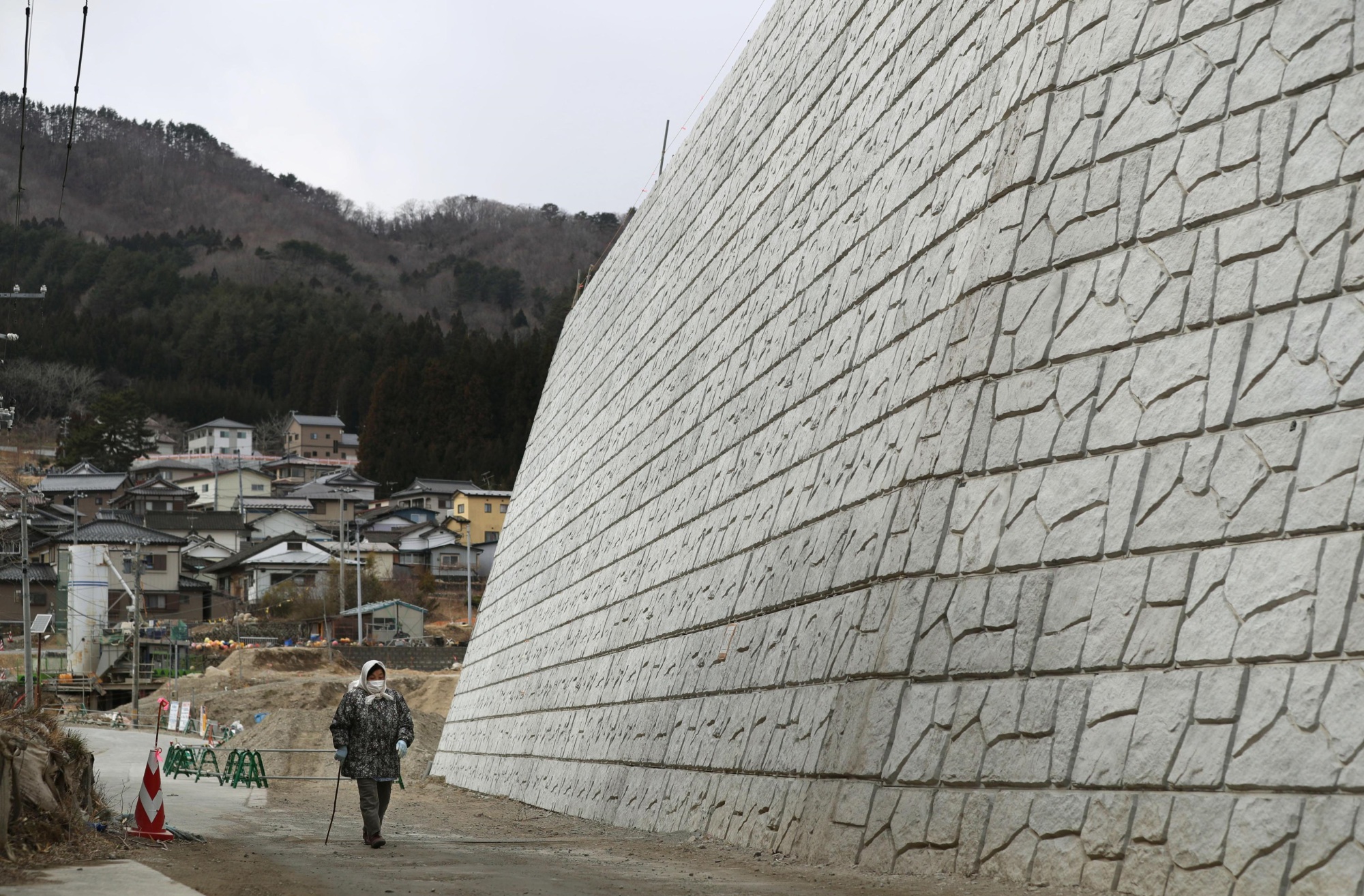 A woman walks along a 14.5-meter-high seawall being built in Kamaishi, Iwate Prefecture, on Thursday. | KYODO