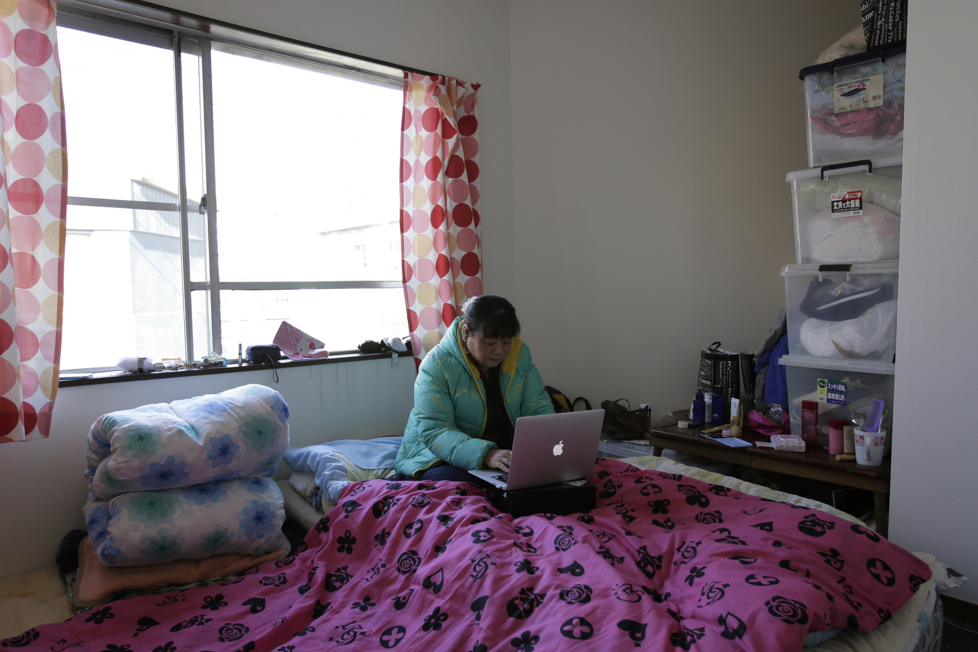 Chinese trainee Tang Xili uses a laptop computer in her room at a shelter managed by a local labor union in Hashima, Gifu Prefecture, in January last year. Japan has been heavily criticized for exploiting foreign trainees as cheap labor. | BLOOMBERG