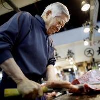 Yutaka Kadono, 80, slices tuna at the Tsukiji market last June. | KYODO
