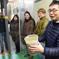 Hiroyuki Tomie, of the Japan Times beer club,  holds a container of the hops, prior to them being added them to the brew kettle. | SATOKO KAWASAKI