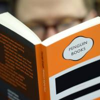 Learning to love Big Brother again: A customer reads a copy of \"1984\" at a bookstore in London. In \"post-truth\" 2017, the dystopian tale George Orwell penned in 1948 is again a best-seller. | BLOOMBERG