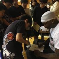 Larry Williams signs autographs for students earlier this month in Kansai. Between 700 and 800 Japanese youth attended his basketball clinics in Osaka and Kobe. | LARRY WILLIAMS
