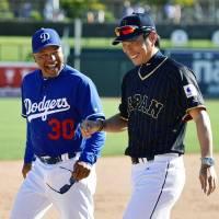 Japan manager Hiroki Kokubo (right) shares a joke with Los Angeles Dodgers counterpart Dave Roberts after their game on Sunday in Glendale, Arizona. | KYODO