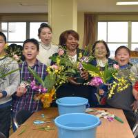 Solange P. Weya, wife of the Cote d\'Ivoire ambassador (center), Ikebana International members and sixth-grade students show off their projects at an Ikebana Workshop, the fifth such workshop since the Great East Japan Earthquake and tsunami, at IItoyo Elementary School in Soma, Fukushima Prefecture, on March 2. | IKEBANA INTERNATIONAL