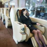 A woman tries out a seat in a new luxury tour bus Wednesday in Tokyo. Travel agency JTB Corp. said it will start selling related tours this month. | KYODO