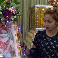 Jiranuch Trirat, mother of an 11-month-old infant who was killed by her father — who broadcast the murder on Facebook — stands next to a picture of her daughter at a temple in Phuket, Thailand, on Tuesday. Facebook again draws fire after Thai man broadcasts baby daughter's murder