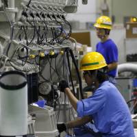Workers assemble an engine at the Mitsubishi Heavy Industries Engine &amp; Turbocharger plant in Sagamihara, Kanagawa Prefecture, in July 2016. The maker has cut the number of workers on its turbocharger production lines at the plant by more than 80 percent. | BLOOMBERG