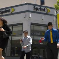 Pedestrians walk past a Sprint store in San Francisco. Sprint is under pressure to make a merger deal, with billions of dollars of debt coming due and a network that needs investment. | BLOOMBERG