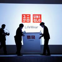 People prepare for a news conference by Fast Retailing Co. in Tokyo on March 16. | REUTERS