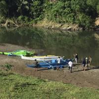 People stand by boats which the military said were used by Abu Sayyaf militants to enter the Ibananga River in Bohol province, central Philippines, as government troopers continue clearing operations, in this undated photo provided on April 12, 2017. | ARMED FORCES OF THE PHILIPPINES / VIA AP