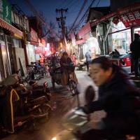 People ride through a “hutong” alleyway in Beijing in December. Beijing's 'hutongs': Chinese village life preserved in the big city