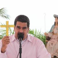 Venezuelan President Nicolas Maduro holds a Palm cross as he speaks during his weekly broadcast “Los Domingos con Maduro” (“The Sundays with Maduro”) in Barquisimeto, Venezuela, Sunday. After blocking ouster referendum, embattled Venezuela leader welcomes regional vote
