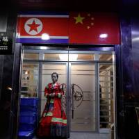 A woman wearing traditional Korean costume waits at the door of a North Korean restaurant in Dandong city, in north China’s Liaoning province, on March 30. For North Korea and China, defense pact proves a complicated document