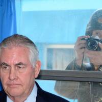 U.S. Secretary of State Rex Tillerson is briefed by U.S. Gen. Vincent K. Brooks, commander of the United Nations Command, Combined Forces Command and United States Forces Korea (not pictured), as a North Korean soldier takes a photograph through a window at the border village of Panmunjom, South Korea, March 17. | KOREA POOL / YONHAP / VIA REUTERS