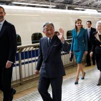 Spain’s King Felipe (left), Queen Letizia (third left), and Emperor Akihito (second left) and Empress Michiko smile to well-wishers as they board a shinkansen to depart on a one-day trip to Shizuoka from Tokyo Station on Friday. | POOL / REUTERS