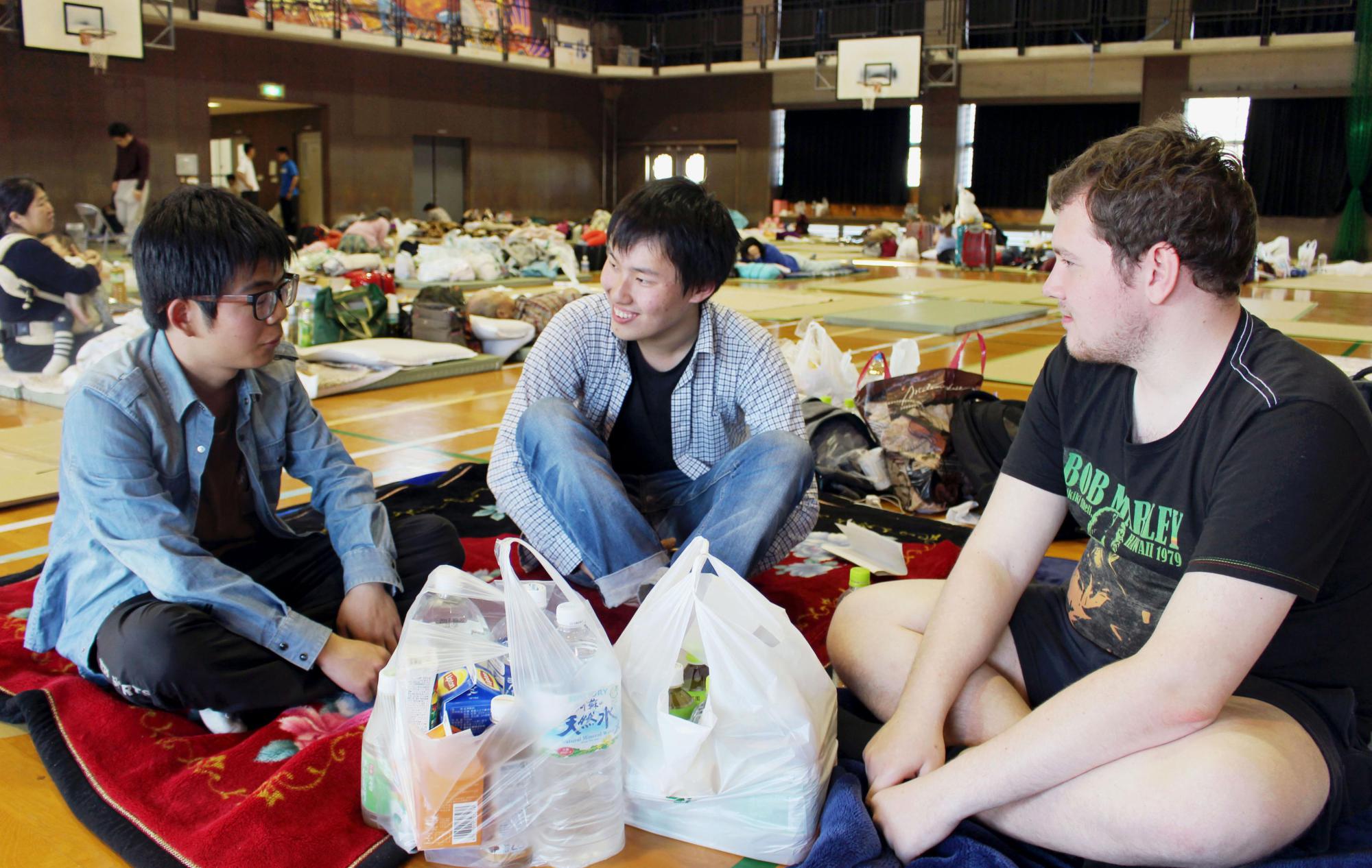 Foreign students chat in a gymnasium used as an evacuation shelter in Kumamoto on April 17 last year, following a series of powerful earthquakes in the region. | KYODO