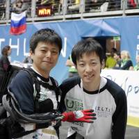 Masahiro Kasuya (right) poses with \"pilot\" Kazuya Maeda, who wears a prosthetic hand he developed, during Cybathlon 2016, the first international competition of robotic technologies for people with disabilities, in Switzerland in October. | MELTIN MMI CO.