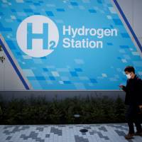 A passer-by walks in front of a hydrogen station in Tokyo on April 24. The government is betting heavily on hydrogen as a fuel of the future. Norway takes on Australia in bid to fulfill Japan's hydrogen society dream