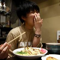 A customer reacts as she eats an ‘insect tsukemen’ — ramen noodles topped with fried worms and crickets — at Ramen Nagi in Tokyo. Ramen flavored with insects attracts thrillseekers in Tokyo