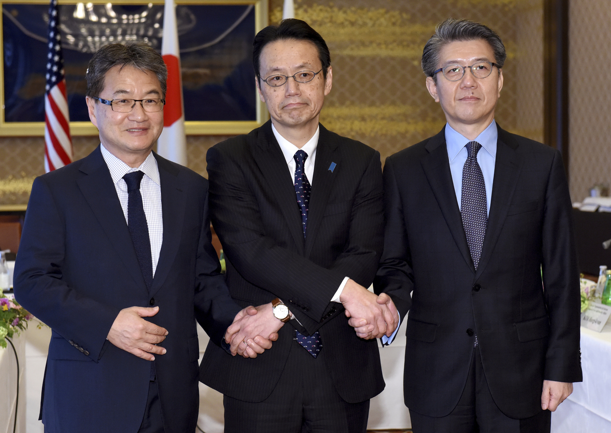Joseph Yun (from left), U.S. special representative for North Korea policy, Kenji Kanasugi, director-general of the Foreign Ministry's Asian and Oceanian Affairs Bureau, and Kim Hong-kyun, special representative for Korean Peninsula peace and security affairs at the South Korean Foreign Ministry, join hands before their meeting about North Korean issues at the Iikura Guesthouse in Tokyo on Tuesday. | AP