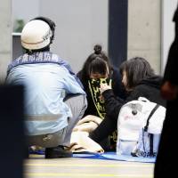 An emergency services worker attends women who felt unwell during a rock concert Saturday evening at Makuhari Messe hall in the city of Chiba. | KYODO