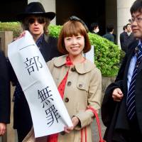 Artist Megumi Igarashi, known as Rokudenashiko (Good-For-Nothing Girl), holds up a sign in front of the Tokyo High Court last Thursday showing the court\'s decision finding her guilty of obscenity for distributing 3-D scans of her genitalia. | DAISUKE KIKUCHI