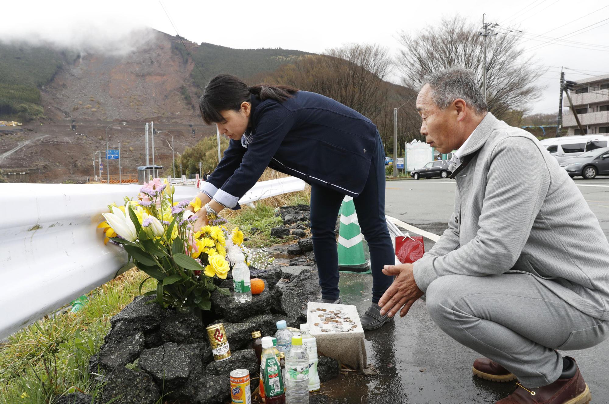 Shinobu and Takuya Yamato lay flowers April 8 near the collapsed Aso Ohashi Bridge in Minamiaso, Kumamoto Prefecture, where their son is believed to have died in last year's deadly earthquakes. | KYODO
