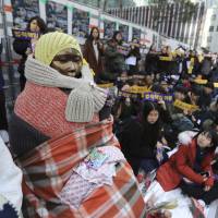 During a weekly rally in front of the Japanese Embassy in Seoul, students gather near a statue of a girl representing the thousands of Korean women forced to provide sex for Japanese troops before and during World War II. | AP