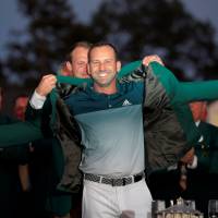 Masters champion Sergio Garcia is helped into the winner’s green jacket by 2016 champion Danny Willett on Sunday in Augusta, Georgia. Garcia wins Masters for long-awaited first major title