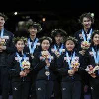 Japan skaters celebrate the team\'s first-place finish on the podium at the World Team Trophy on Saturday night. | REUTERS