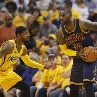 Cleveland’s LeBron James (right) assesses his options as Indiana’s Paul George defends on Thursday. Huge rally carries Cavs past Pacers