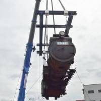 A steam train engine is hoisted into the air ahead of its reassembly in the town of Aridagawa, Wakayama Prefecture, on Tuesday. Later this summer the train will run along a 400-meter stretch of track at the Aridagawa Train Park. | KYODO
