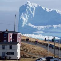 Residents of Ferryland, Newfoundland, view the first iceberg of the season as it passes the South Shore, also known as \"Iceberg Alley,\" on Sunday. Icebergs along the eastern coast of Canada, often lurking in thick fogs, have sunk many ships, including the Titanic. | REUTERS