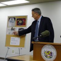 Stephen Levins, executive director of Hawaii’s Office of Consumer Protection, gestures to photos of metal shards released when air bags exploded on Wednesday. Hawaii sues Ford, Nissan and Toyota for using dangerous Takata air bags