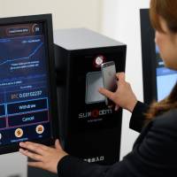 A BITPoint Japan employee demonstrates a bitcoin ATM in Tokyo on Thursday. The firm plans to increase acceptance of the digital currency at more retail outlets nationwide. BITPoint in talks to add bitcoin payments to outlets across Japan