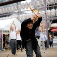 Elderly and middle-aged people exercise with wooden dumbbells during a health promotion event to mark Respect for the Aged Day at a temple in Tokyo\'s Sugamo district, an area popular among the elderly, last September. | REUTERS
