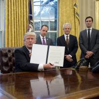 President Donald Trump holds up an executive order withdrawing the U.S. from the Trans-Pacific Partnership in Washington on Jan. 23. The 11 other nations in the TPP will meet in July to discuss what comes next. | BLOOMBERG