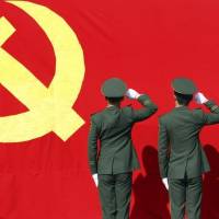 Paramilitary policemen hold their fists in front of a flag of Communist Party of China as they attend an oath-taking rally to ensure the safety of the 18th National Congress of the Communist Party of China (CPC), at a military base in Hangzhou, Zhejiang province, in November 2012. | CHINA DAILY / VIA REUTERS