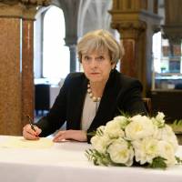British Prime Minister Theresa May writes a message in the book of condolences for victims of Monday\'s attack on Manchester Arena on Tuesday at Manchester Town Hall. | REUTERS