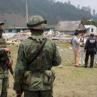 Mexican soldiers stand next to the delimited area of the rubble left by a blast that occurred at a fireworks warehouse in San Isidro, Chilchotla, Puebla state, Mexico, Tuesday. Mexico fireworks warehouse blast kills 14, including 11 children