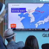 People watch a news report on North Korea firing a ballistic missile, at a railway station in Seoul on Sunday. | YONHAP / VIA REUTERS